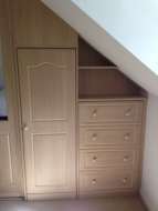 2 cupboards fitted into the eave of the room, one of which is designed to look like drawers