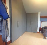 Hinged wardrobes fitted into a space with a sloped cieling and wrapping around the corner
