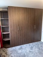 Fitted hinged wardrobe with open end shelves before doors with doors
