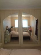 An arch spanning 2 doors with mirror inserts in a pearwood finis (straight on view)