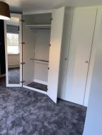 L-shaped hinged wardrobe in white for a walk in wardrobe with doors open showing hidden mirror