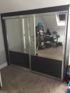 Mirror doors with a black woodgrain panel to the bottom, fitted in Leven